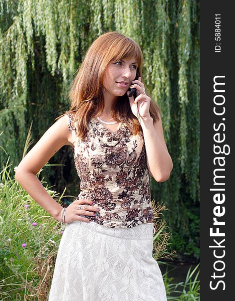 Young beautiful woman with chestnut-coloured hair is talking by the mobile. Young beautiful woman with chestnut-coloured hair is talking by the mobile