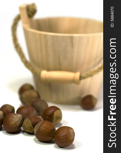 Hazelnuts and wooden basket on white background