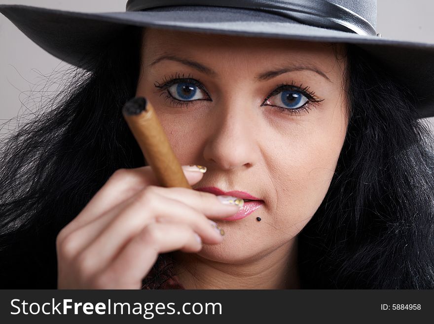 An image of woman in the hat smokes cigars