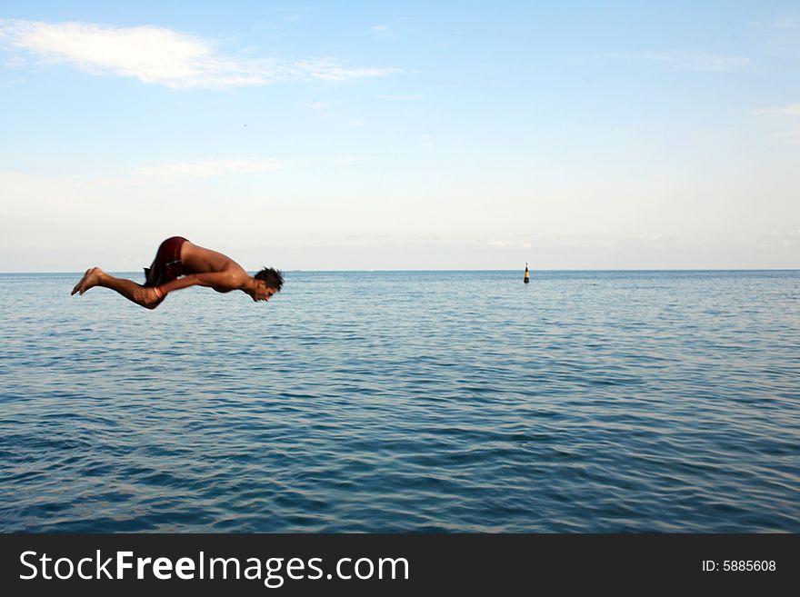 The man jumping in water from a pier. The man jumping in water from a pier