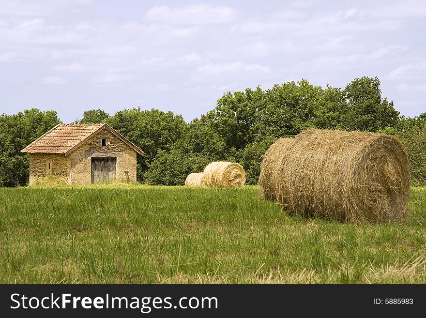 Small cottage in a French field next to several large haystacks. Small cottage in a French field next to several large haystacks