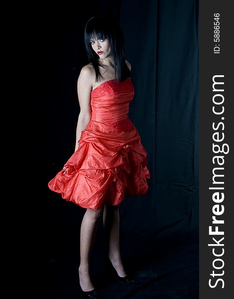 Full length of a young lady with black hair and red lipstick in a red dress looking right. Full length of a young lady with black hair and red lipstick in a red dress looking right