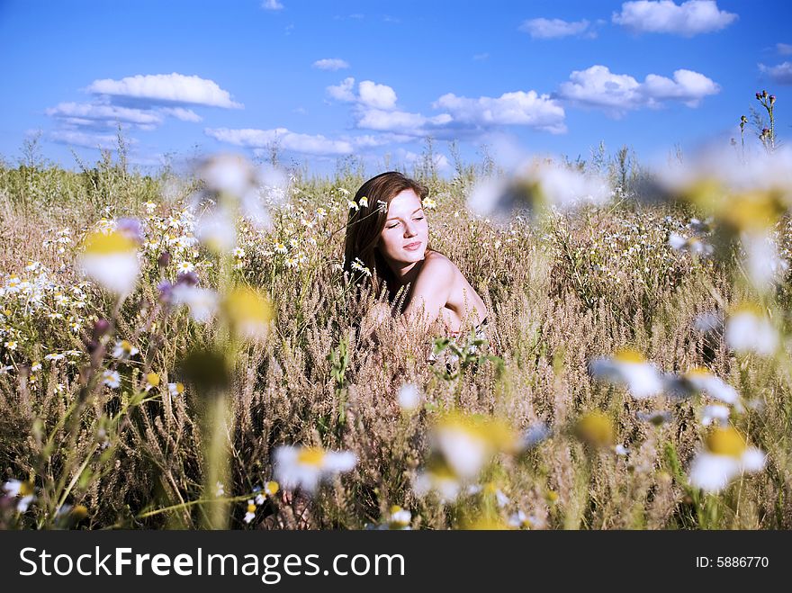 Beauty young woman sitting in flowers under blue sky. Beauty young woman sitting in flowers under blue sky