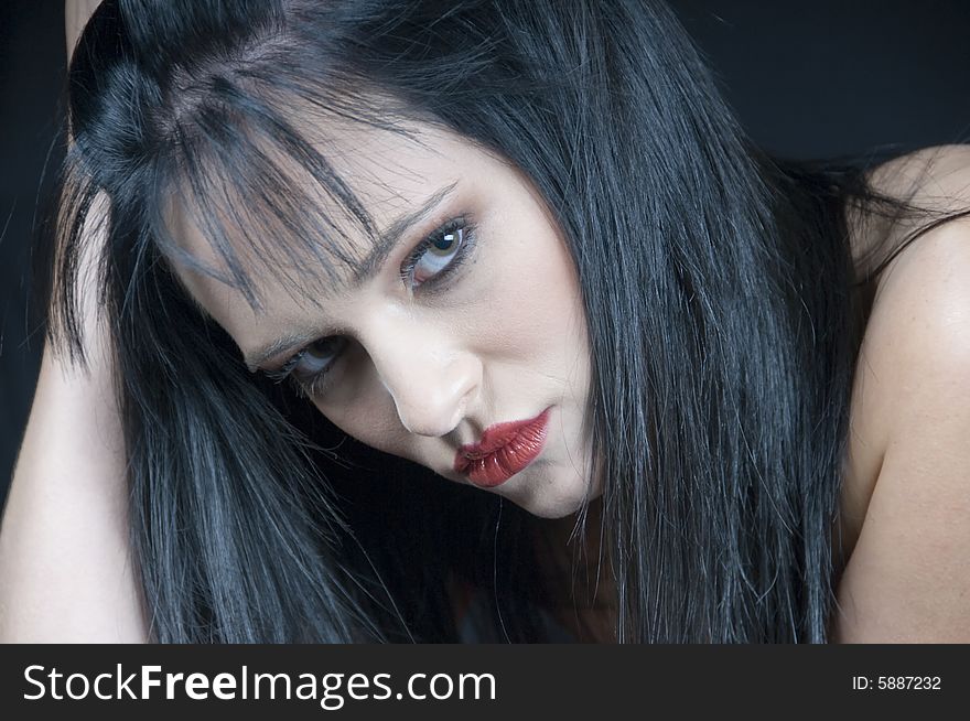 Head and shoulders landscape of a young lady with black hair and red lipstick looking serious. Head and shoulders landscape of a young lady with black hair and red lipstick looking serious.
