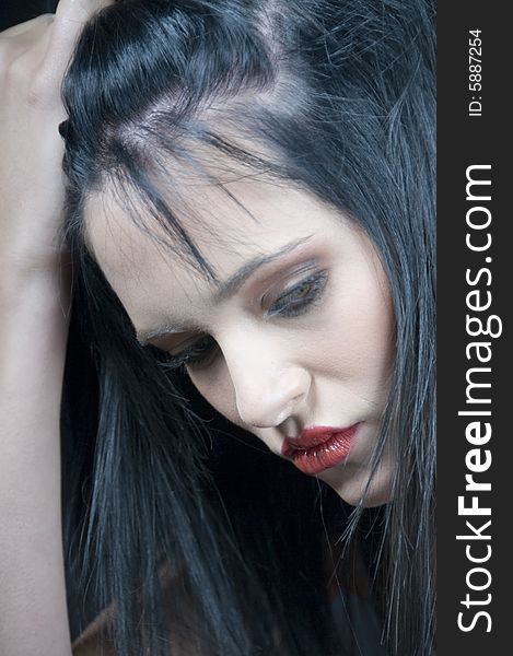 Head and shoulders of a young lady with black hair and red lipstick looking serious with hand on head. Head and shoulders of a young lady with black hair and red lipstick looking serious with hand on head.