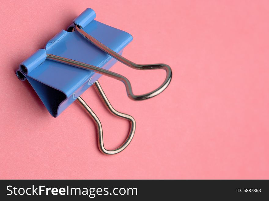 Close-up of blue metal paperclip on pink background. Close-up of blue metal paperclip on pink background