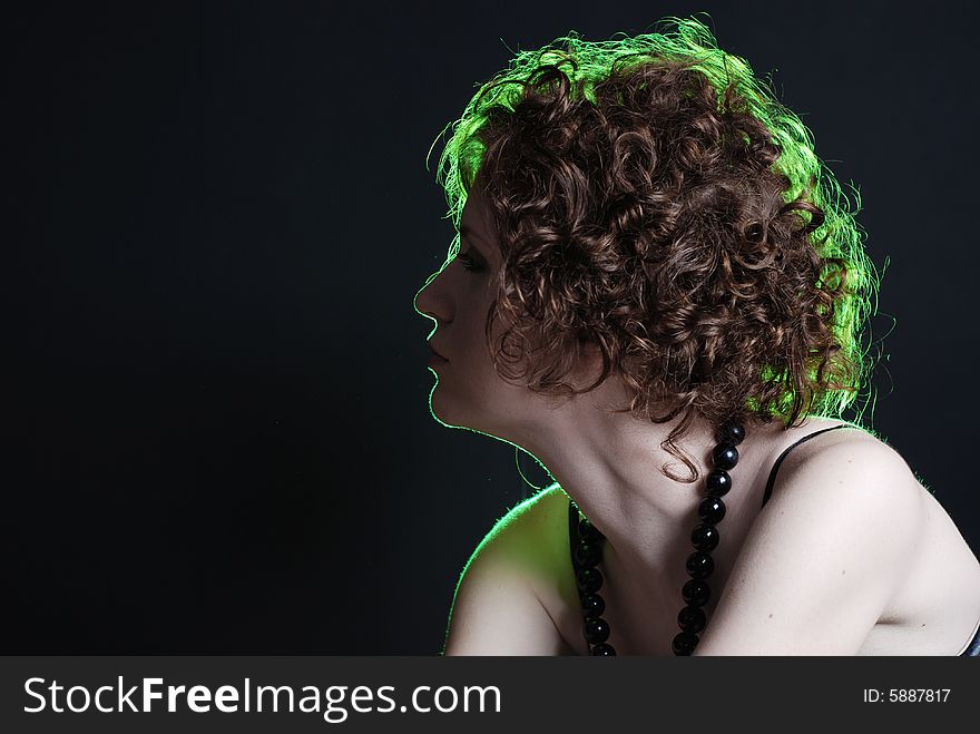 Beauty portrait of woman with green light on hair at black background