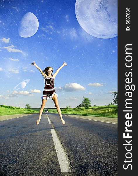 Happy woman jumping over the road under blue sky with planets. Happy woman jumping over the road under blue sky with planets