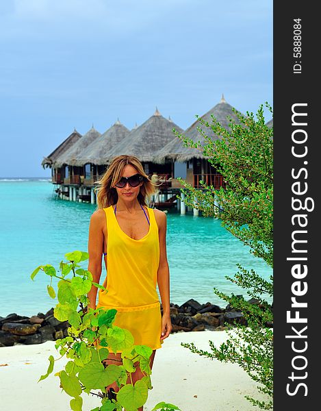 Woman standing on the tropical beach with bungalows in the background. Woman standing on the tropical beach with bungalows in the background