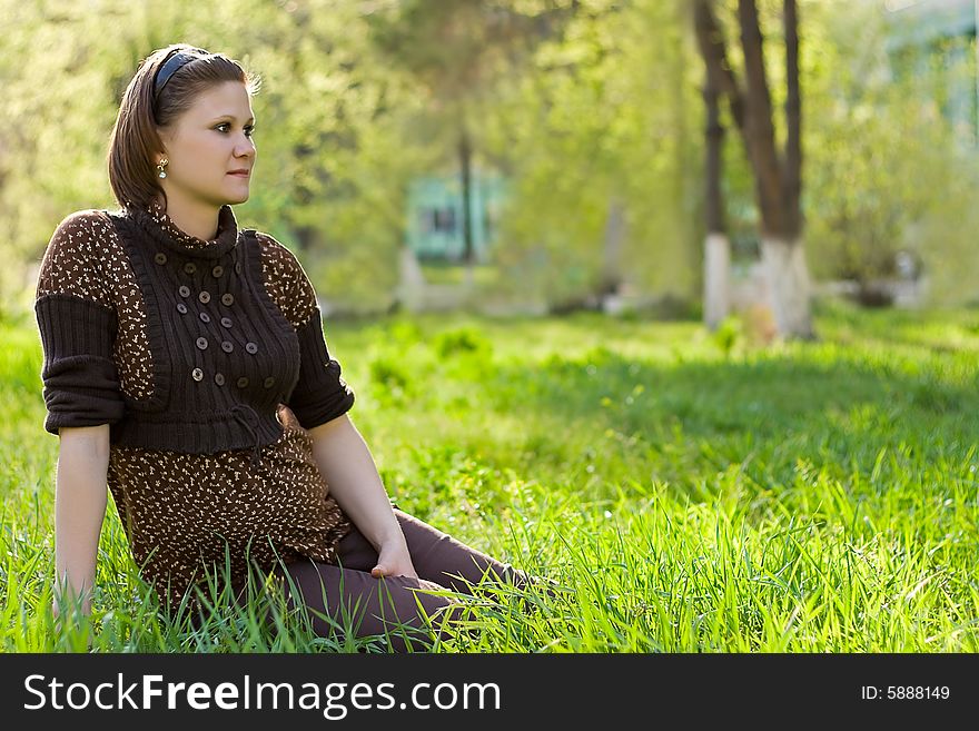 Young beautiful woman sitting on the grass, copy space for the text