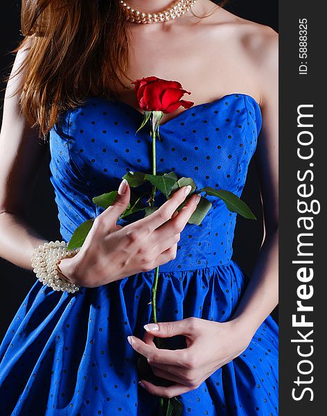 Beauty young woman in blue dress with rose at black background