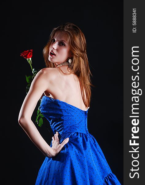 Beauty young woman in blue dress with rose at black background