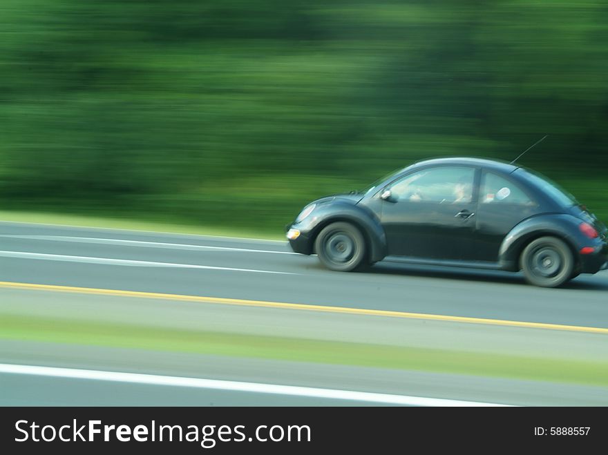 Speeding black car with blurred trees. Speeding black car with blurred trees