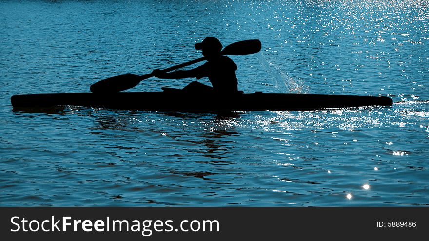 A black silhouette of a sportsman on a paddle (kayak). A black silhouette of a sportsman on a paddle (kayak)