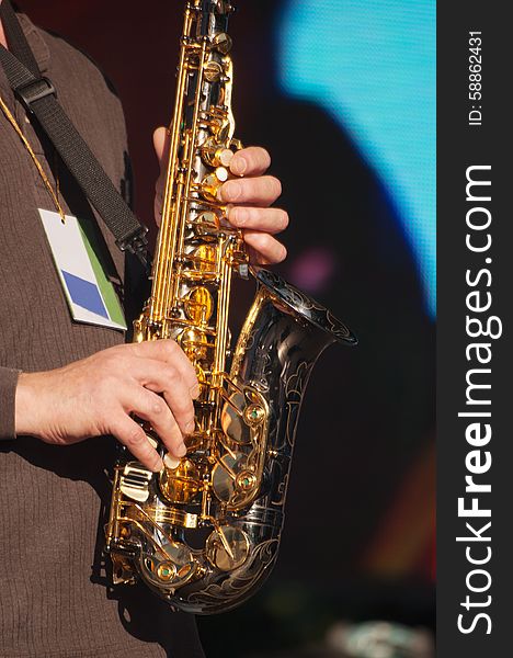 Hands of saxophonist in concert outside on summer day closeup