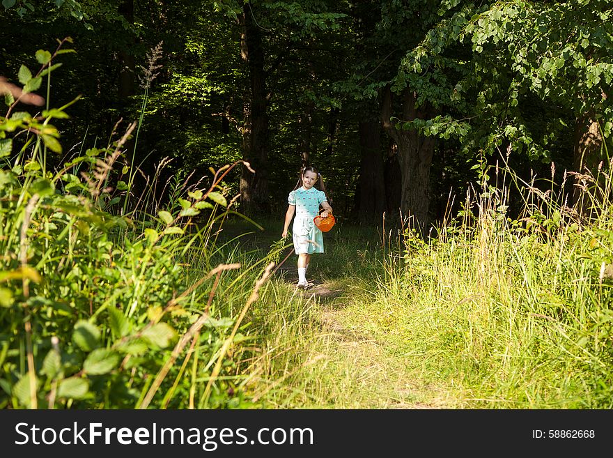 Little smiling girl in green dress goes out of the forest on sunny summer day. Little smiling girl in green dress goes out of the forest on sunny summer day