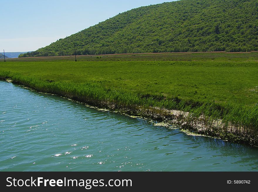 Landscape of emerald river waters in green valley surrounded by hills. Landscape of emerald river waters in green valley surrounded by hills