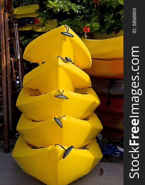 Five yellow kayaks stacked at a boat rental