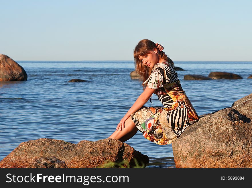 Young lady sitting on stones and smoothes her hair. Young lady sitting on stones and smoothes her hair