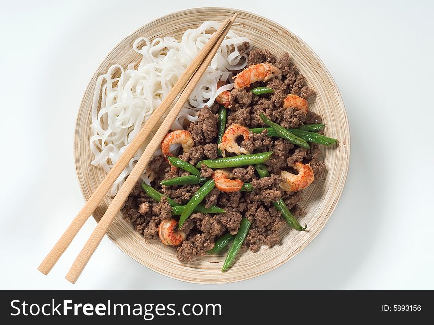 Meal of minced meat with prawns, string beans and noodles, woodeen chopsticks