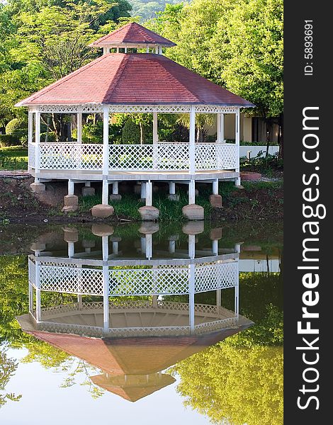 A white gazebo and red roof reflected in the lake. A white gazebo and red roof reflected in the lake