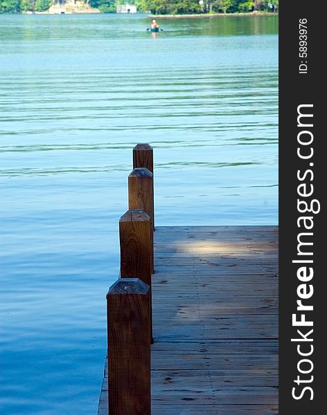 A dock area in the early morning at the water and a kayak in the distance.  It has a very peaceful and quiet feel to it. A dock area in the early morning at the water and a kayak in the distance.  It has a very peaceful and quiet feel to it.