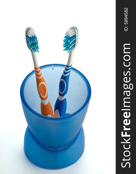 Two toothbrushes in blue cup isolated on white background