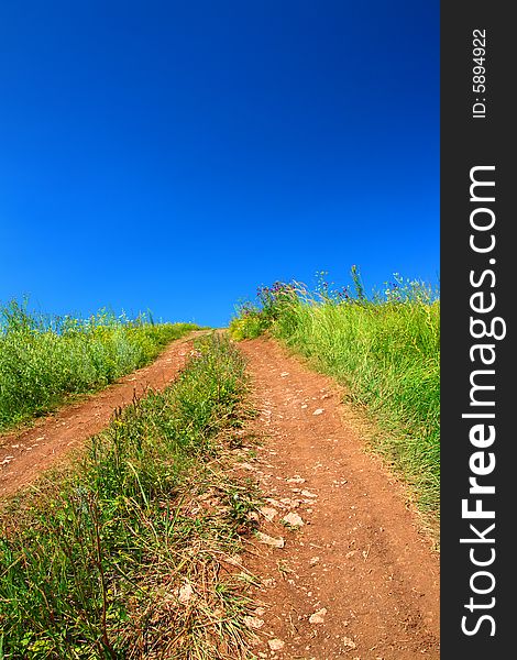 Rural road uphill under blue sky