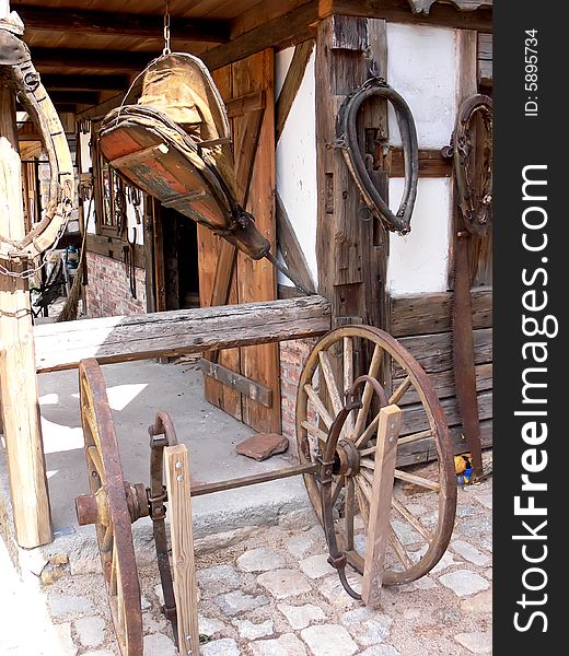 A view at the blacksmith workshop. Old bellows,  wooden wheels and horse items. A view at the blacksmith workshop. Old bellows,  wooden wheels and horse items.