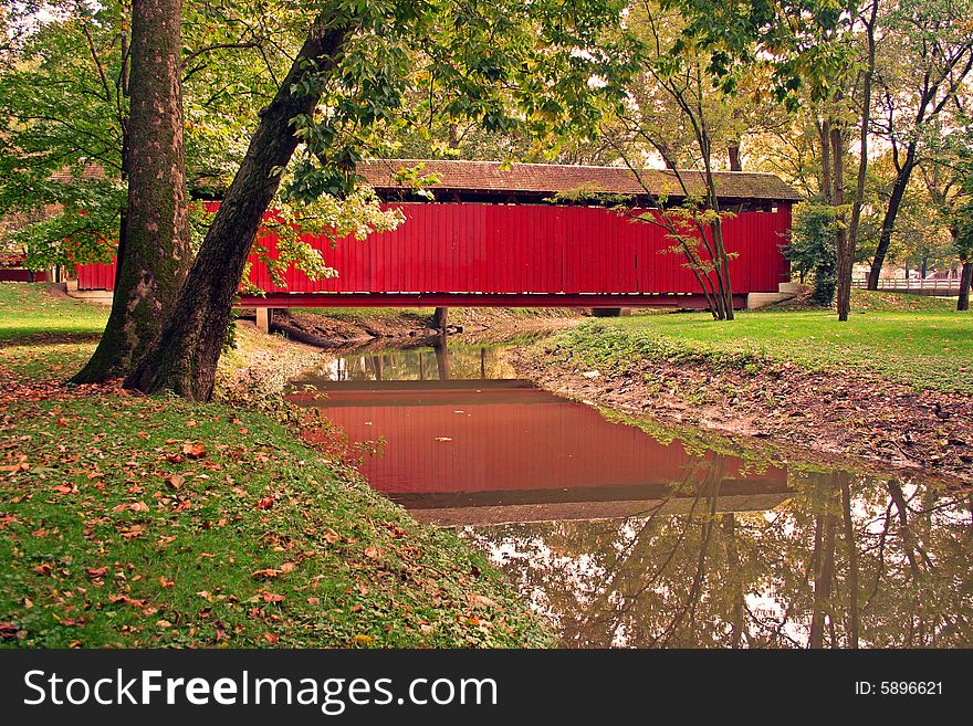Covered bridge early autumn with reflection in stream