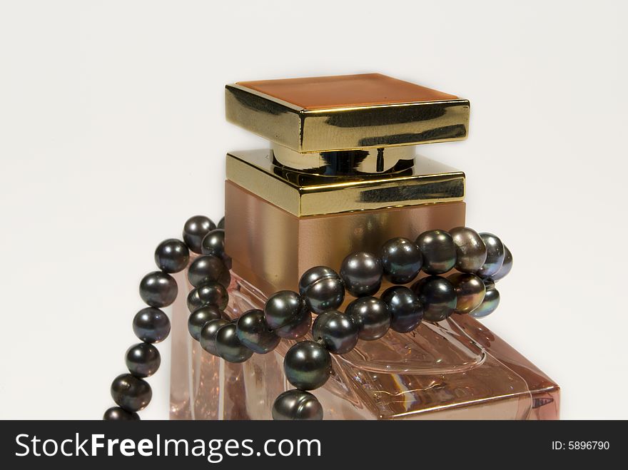 A bottle of expensive perfume and a necklace of real pearls isolated on a white background. A bottle of expensive perfume and a necklace of real pearls isolated on a white background.