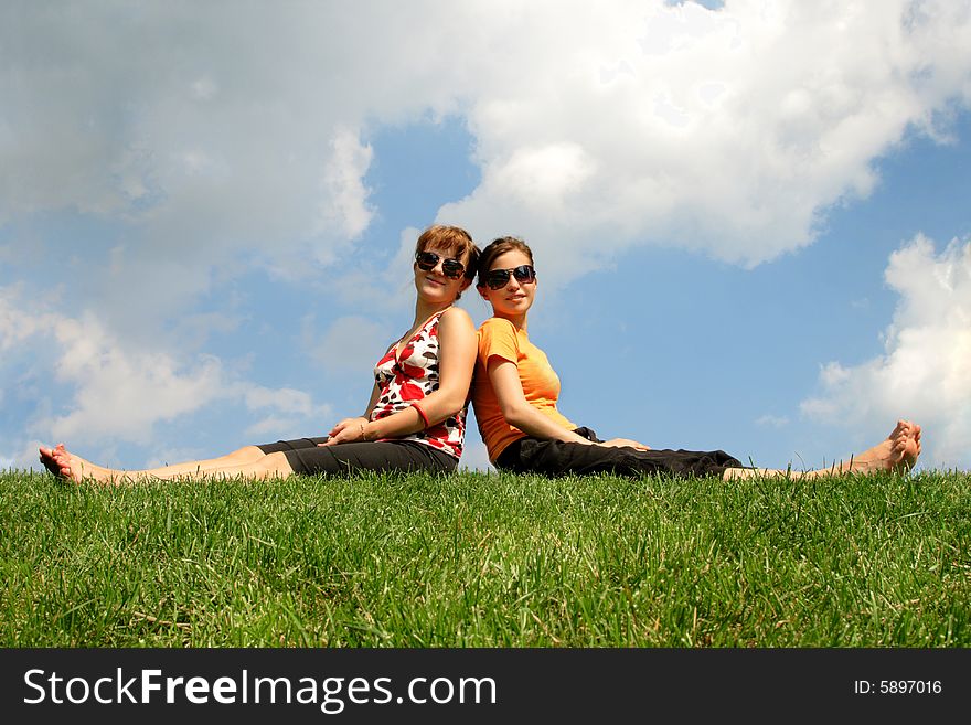 Friends sitting on the grass against cloudy sky