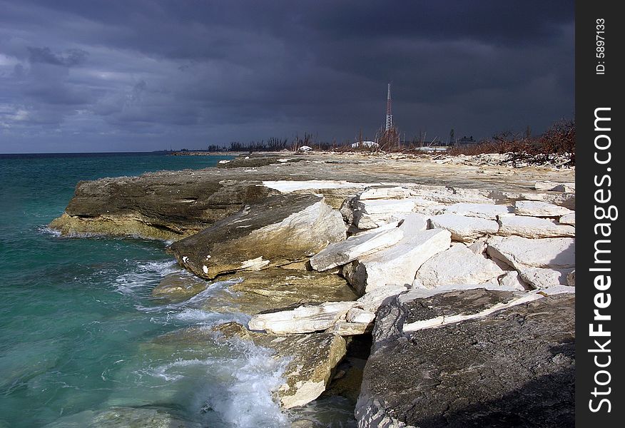 The view of eroded hostile beach in Freeport with stormy sky in a background (Grand Bahama Island, The Bahamas). The view of eroded hostile beach in Freeport with stormy sky in a background (Grand Bahama Island, The Bahamas).
