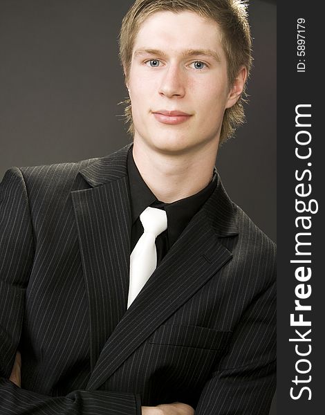 Portrait of handsome young businessman on gray background