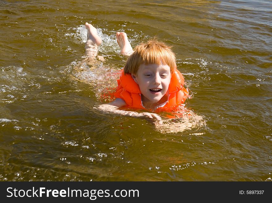 Little swimmer floating on the river. In life jacket.