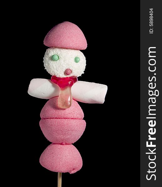 A male figurine made out of candies on a stick over a black background. A male figurine made out of candies on a stick over a black background.