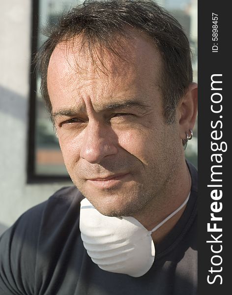 Close up of man's face. He is wearing a mask around his neck. He is looking concerned or thoughtful. Vertically framed shot. Close up of man's face. He is wearing a mask around his neck. He is looking concerned or thoughtful. Vertically framed shot.