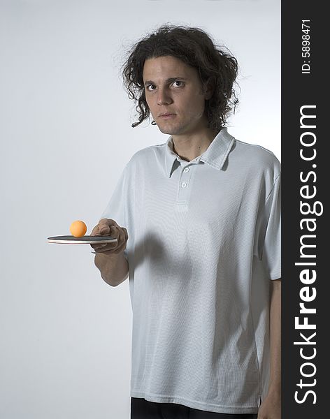 Man holding a ping pong paddle and balancing a ball on top. He is looking at the camera. Vertically framed shot. Man holding a ping pong paddle and balancing a ball on top. He is looking at the camera. Vertically framed shot.