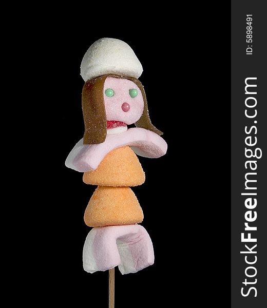 A female figurine made out of candies on a stick over a black background. A female figurine made out of candies on a stick over a black background.