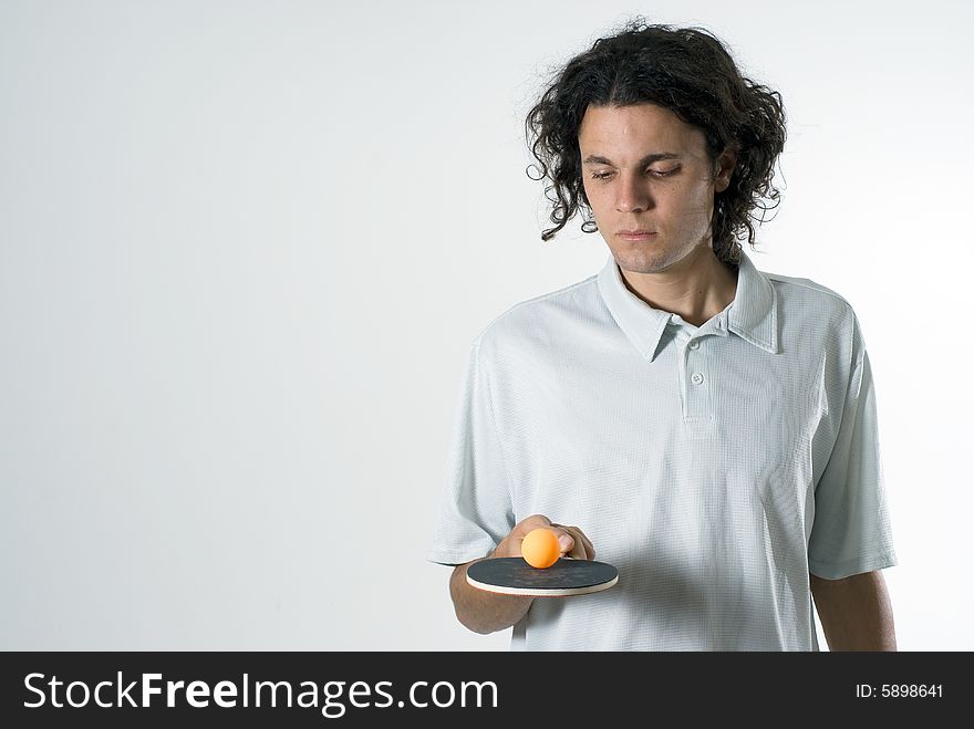 Man looks at a table tennis racket and ball as he balances it. Horizontally framed photograph. Man looks at a table tennis racket and ball as he balances it. Horizontally framed photograph