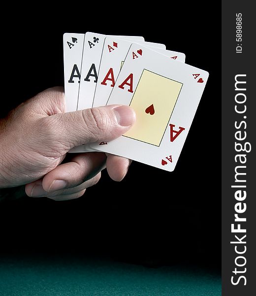 A man's hand holding four aces isolated on black background.