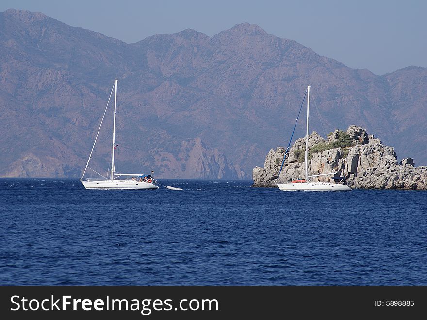 Two sailboats in front of small isle. Two sailboats in front of small isle