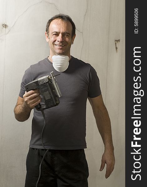 Man standing holding jigsaw with mask around neck. He is looking at camera and smiling. Vertically framed shot. Man standing holding jigsaw with mask around neck. He is looking at camera and smiling. Vertically framed shot.