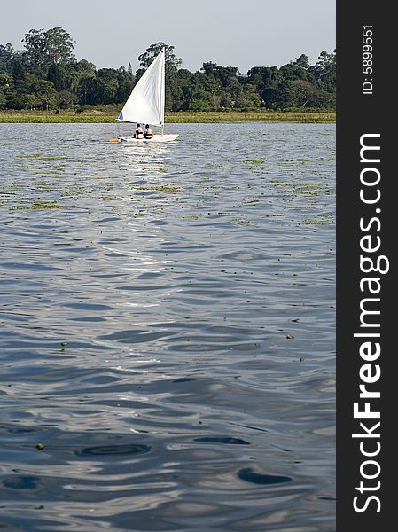 Man and woman sailing across lake. Photo from rear. Vertically framed photo. Man and woman sailing across lake. Photo from rear. Vertically framed photo.
