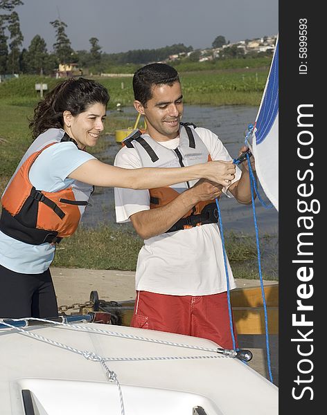 Man and woman smiling while rigging sails on sailboat. Working Together. Vertically framed photo. Man and woman smiling while rigging sails on sailboat. Working Together. Vertically framed photo