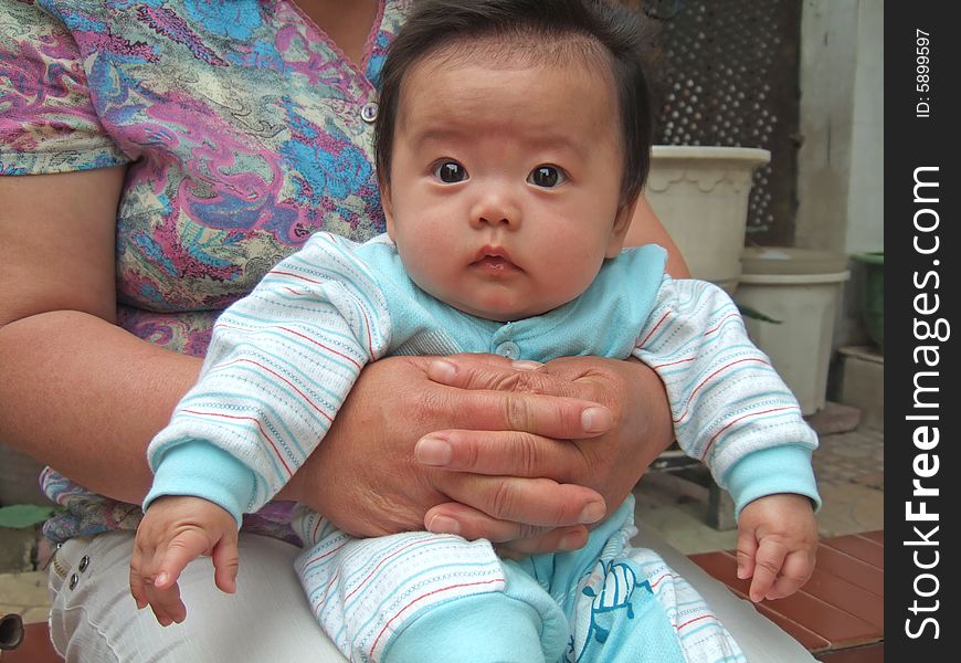 Big eyes infant on her grandmother's leg