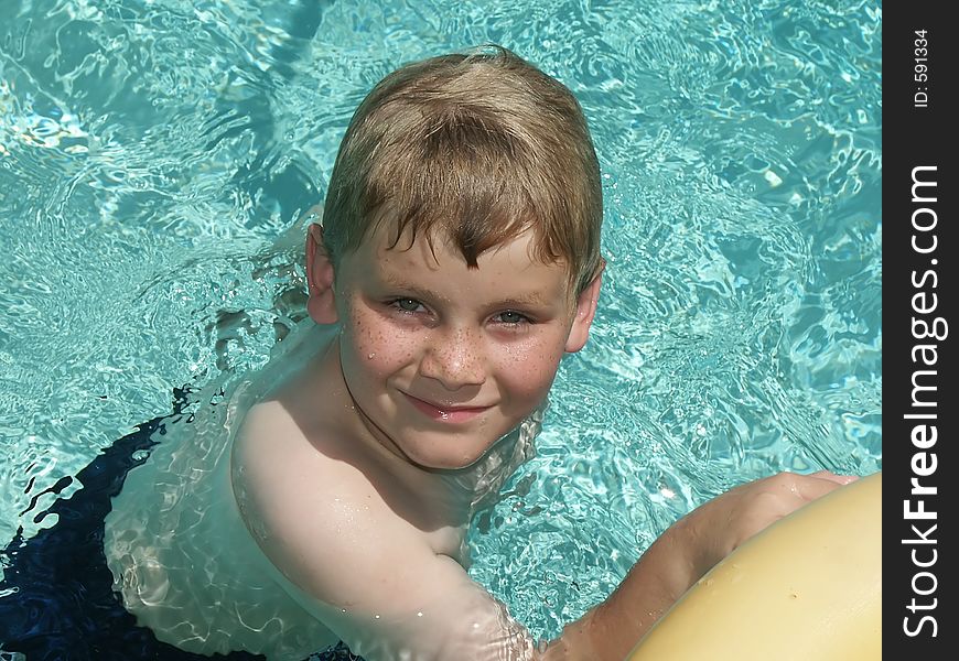 A close-up of a young boy swimming in a pool. A close-up of a young boy swimming in a pool.