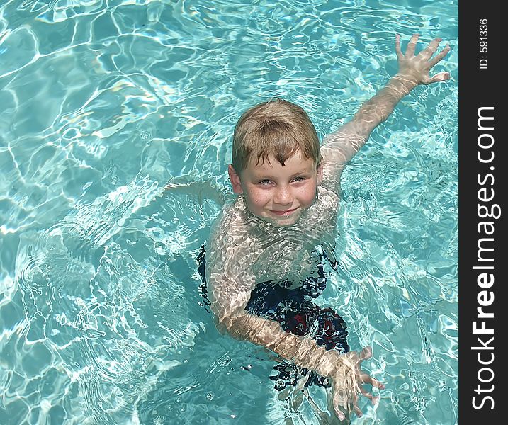 A young boy exercixing in a swimming pool. A young boy exercixing in a swimming pool.