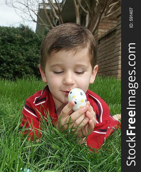 A young boy holding and inspecting a decorated Easter egg. A young boy holding and inspecting a decorated Easter egg.