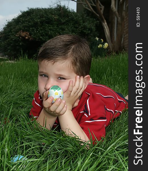 A youngboy looking unhappy while holding a decorated Easter egg. A youngboy looking unhappy while holding a decorated Easter egg.